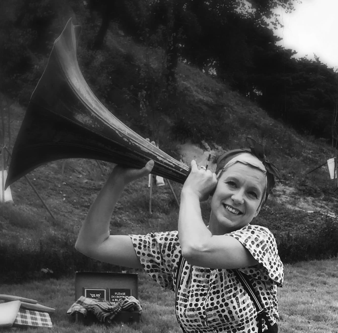 An image of a women with a checked blouse holding an old grammer phone to her ear as if listening